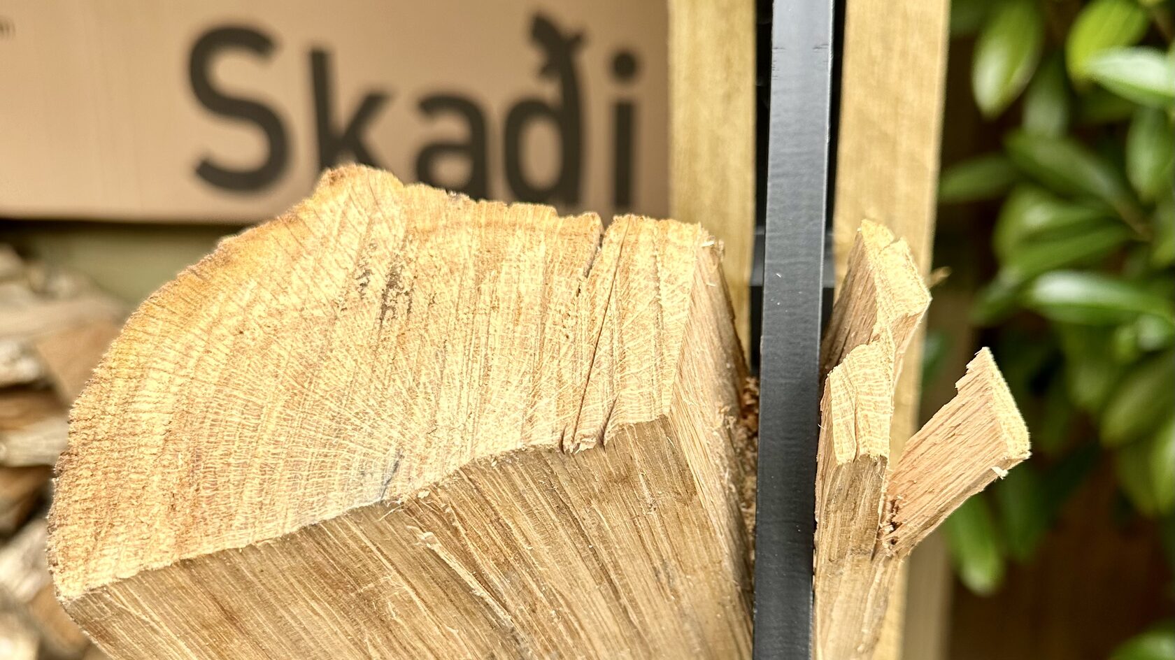 Skadi kindling splitter mid-cut, split wood exposed with Skadi wordmark behind